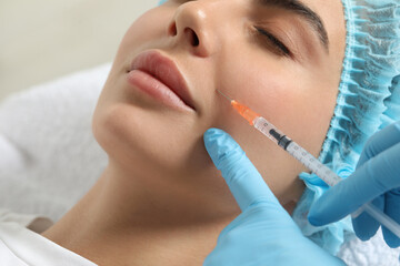 Doctor giving facial injection to young woman in clinic, closeup. Cosmetic surgery