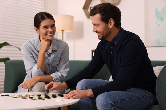 Couple playing checkers at coffee table at home