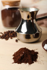 Heap of coffee powder with beans on light wooden table, closeup