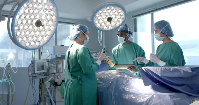 Diverse female and male surgeons in masks discussing during operation, copy space, slow motion