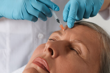 Naklejka premium Doctor giving facial injection to senior woman in clinic, closeup. Cosmetic surgery