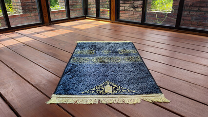 The gray prayer mat or sajadah for prayer or salat on the wooden floor gives a calming and solemn...
