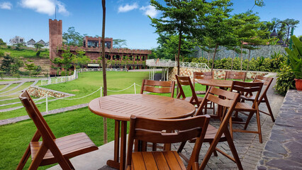 Row of round wooden tables with chairs in an outdoor cafe or restaurant with beautiful views of the surrounding nature