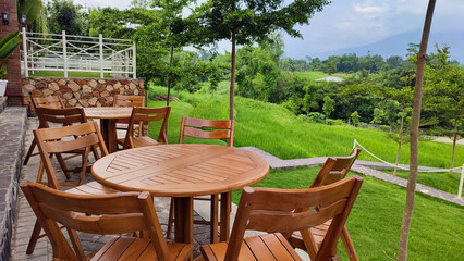 Row of round wooden tables with chairs in an outdoor cafe or restaurant with beautiful views of the surrounding nature