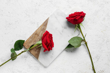 Board with beautiful red roses on light background