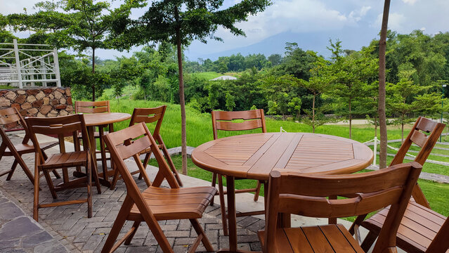 Row of round wooden tables with chairs in an outdoor cafe or restaurant with beautiful views of the surrounding nature