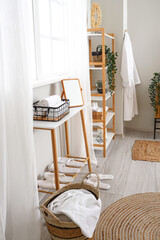 Fototapeta na wymiar Basket with rolled towels and mirror on table near window in bathroom