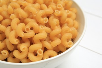 Raw cavatappi pasta in bowl on white table, closeup
