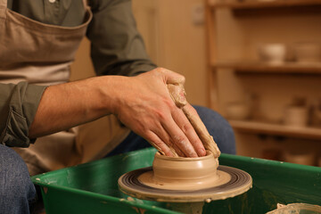 Clay crafting. Man making bowl on potter's wheel indoors, closeup