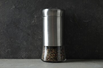 Pepper shaker on light table against grey background, closeup