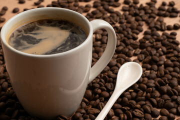 coffee mug with ceramic spoon around coffee beans