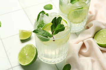 Glass of tasty mojito on white tile background