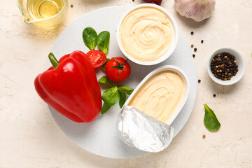 Plastic containers with tasty cream cheese and fresh vegetables on light background