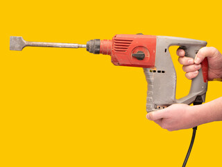 Close up at hands and an impact drill against a lively yellow setting. No face, concept, copy...