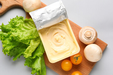 Plastic container with tasty cream cheese, tomatoes and mushrooms on grey background