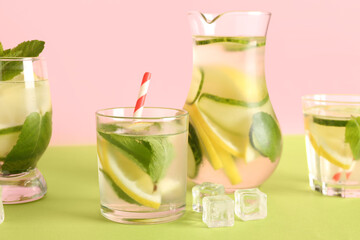 Fototapeta premium Glasses and jug of lemonade with cucumber on green table