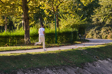 A handsome man maintains his healthy lifestyle as he runs along beautiful natural trails, embodying the essence of fitness, wellness, and vitality in the midst of scenic outdoor surroundings.