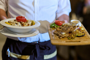 A courteous waiter provides impeccable service to an elderly family and their friends, creating a...