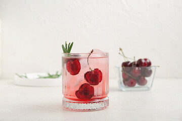 Glass of tasty cherry lemonade with rosemary on white background