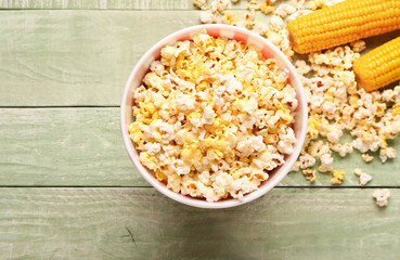 Bucket with tasty popcorn on green wooden background