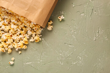 Paper bag with tasty popcorn on grey background