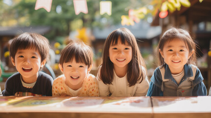日本の小学生4人が私服で横に並んで笑っている写真、背景自然の森、森のようちえん