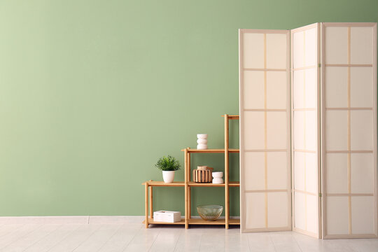 Folding screen and shelving unit near green wall