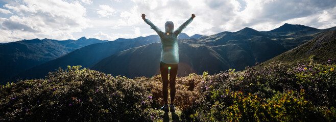 Successful woman outstretched limbs at high altitude mountain peak