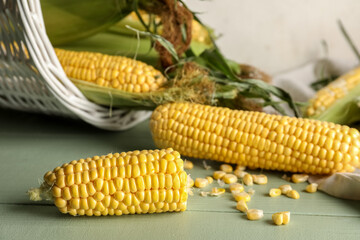 Fresh corn cobs and seeds on green wooden table