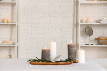 Fototapeta premium Spa composition with burning candles on couch in salon, closeup