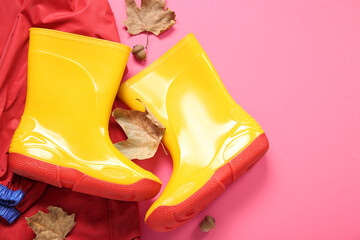 Yellow gumboots with jacket and autumn leaves on pink background