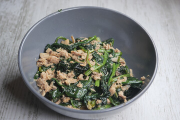 Top view of bowl with cooked spinach on table 
