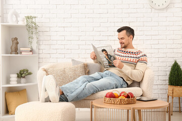 Handsome man reading magazine on sofa in living room