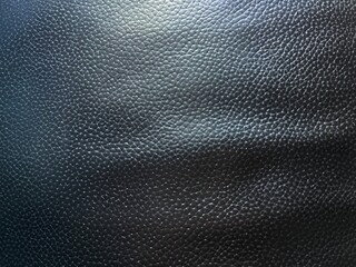 Black abstract blurred leather seat pattern background. There is light shining from above.