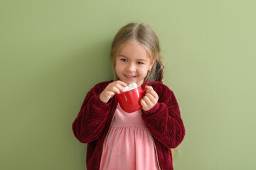 Happy little girl holding cup with marshmallows on green background