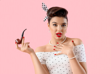 Young pin-up woman with smoking pipe on pink background - obrazy, fototapety, plakaty