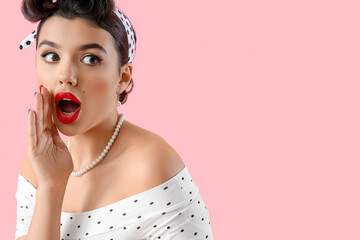 Shocked young pin-up woman gossiping on pink background, closeup