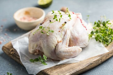 organic raw whole chicken with thyme peppers and garlic on a rustic table - obrazy, fototapety, plakaty