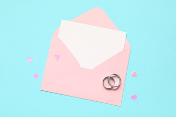 Beautiful wedding rings and envelope on blue background