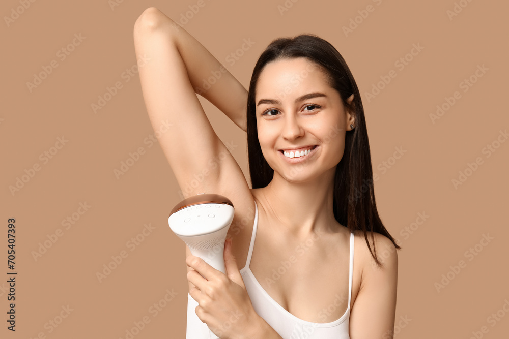 Sticker Happy young woman with modern photoepilator on brown background