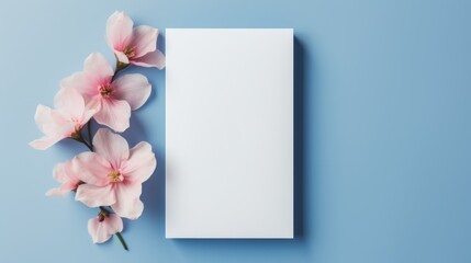 A blank white sheet of paper with delicate pink cherry blossoms on a pastel blue background, inviting artistic or written creativity.