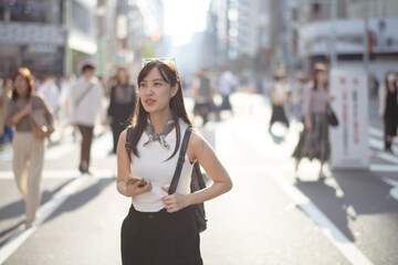 Fototapeta premium Connected in Tokyo, Japanese lady navigating the city with her smartphone, blend of connectivity and urban exploration.
