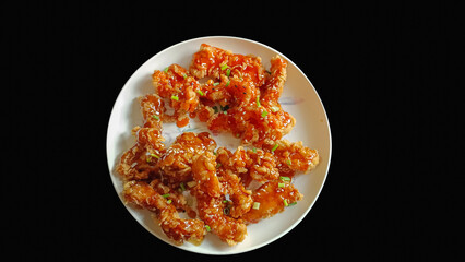 Fried chicken with sauce on isolated black background.