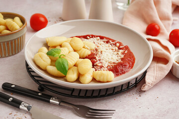 Plate of tasty gnocchi with tomato sauce and cheese on white background
