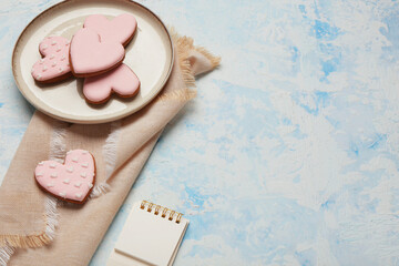 Plate with pink sweet heart shaped cookies on light blue background