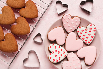 Oven rack and plate with heart shaped cookies, cutters on pink grunge background