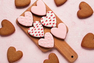Wooden board with tasty heart shaped cookies on pink grunge background. Valentine's Day celebration
