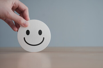 Hand choose happy smiling face for giving customer satisfaction score. Feedback rating and customer...
