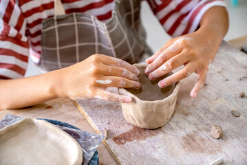 Kids making a craft of a porcelain mug from wet clay