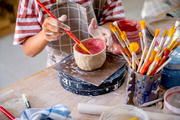 Kids making a craft of a porcelain mug from wet clay